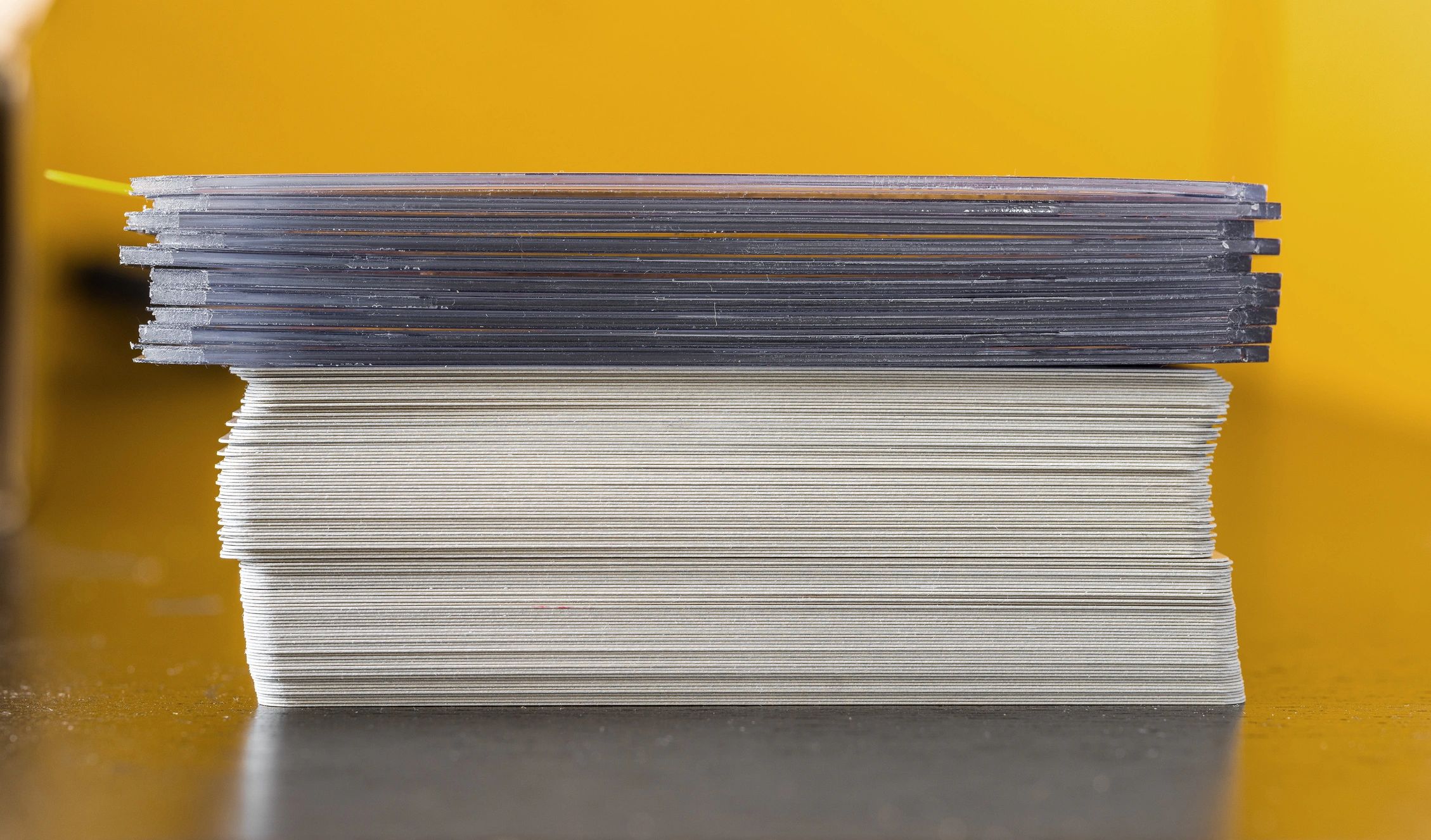 Stack of trading cards and a protective top loader on a dark table